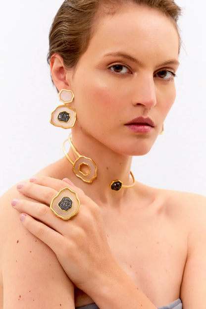 Esta joia combina o contraste de cores clássico com forte simbologia, sendo adornada com Ágata Branca, que promove a paz e a clareza, e Drusa Negra, que atrai energia positiva e proteção. Use este anel em Banho de Ouro 18K para celebrar o seu próprio florescer com elegância.