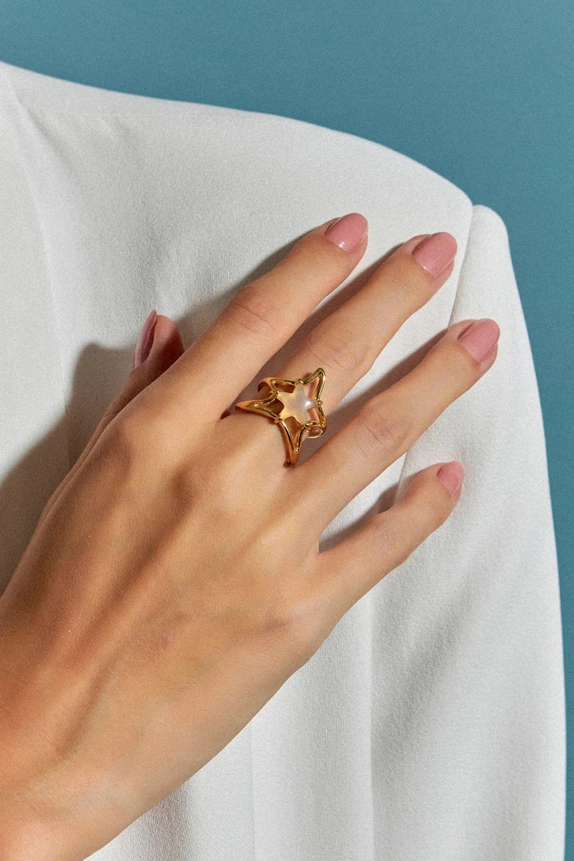 O Anel Brisa com Ágata Branca em Banho de Ouro 18K é uma joia delicada, com uma estrela central em meio a uma onda fluida que a sustenta. A pureza da Ágata Branca é realçada pelo luxo do ouro, criando um visual sofisticado e marcante.