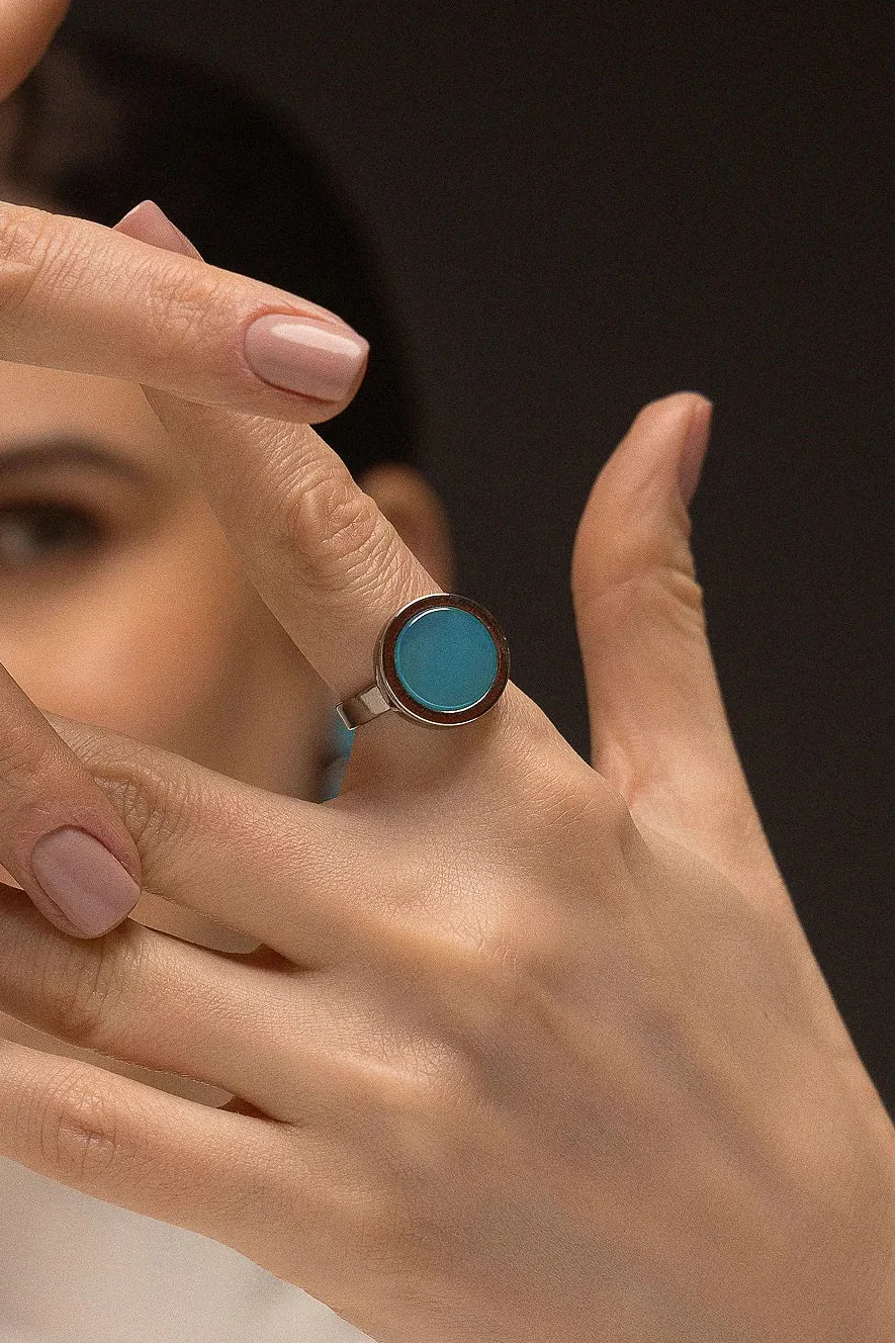 O Anel Eterno - Ágata Azul Céu, da Coleção Singular, une a serenidade das águas à sofisticação do acabamento escuro. A Ágata Azul Céu é reconhecida por promover calma, clareza mental e harmonia nas emoções, criando um contraste moderno e impactante com o metal escuro. Banhado a Ródio Negro, este anel de design contínuo e imponente destaca a suavidade da pedra, sendo a peça ideal para mulheres que buscam um acessório contemporâneo que transmita paz interior com uma personalidade forte.
