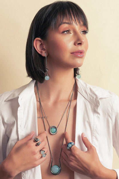 O Anel Sublime em Esmaltado Azul Anil e Ágata Azul Céu, com Banho de Ródio Negro, é uma peça sofisticada e moderna. A Ágata Azul Céu Liso harmoniza-se com o esmalte em tom azul anil, criando um visual elegante e marcante que se integra ao acabamento escuro do ródio.