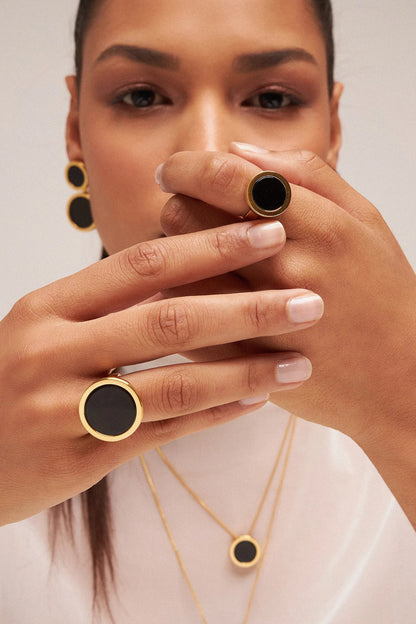 O Anel Único - Obsidiana Negra, da Coleção Singular, é uma joia de grande força e proteção. A Obsidiana Negra é uma poderosa pedra de proteção energética, purificação e aterramento, ideal para quem busca segurança e estabilidade. Banhado a Ouro 18K e com seu design imponente, este anel transforma a simplicidade em um acessório marcante, representando a força e a singularidade da mulher que o veste.