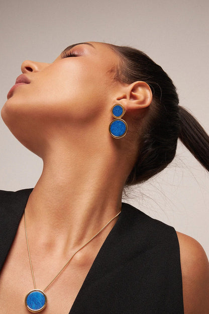 O Brinco Nobre - Feldspato Azul Anil, integrante da Coleção Singular, é uma joia de elegância profunda e magnética. O Feldspato Azul Anil é uma pedra associada à expansão da consciência, à intuição e à clareza mental, evocando a serenidade dos oceanos e a imensidão do céu. Banhado a Ouro 18K, este brinco de design imponente destaca a cor intensa e o brilho sofisticado da gema, sendo a peça ideal para mulheres que buscam um acessório de presença marcante e significado espiritual.